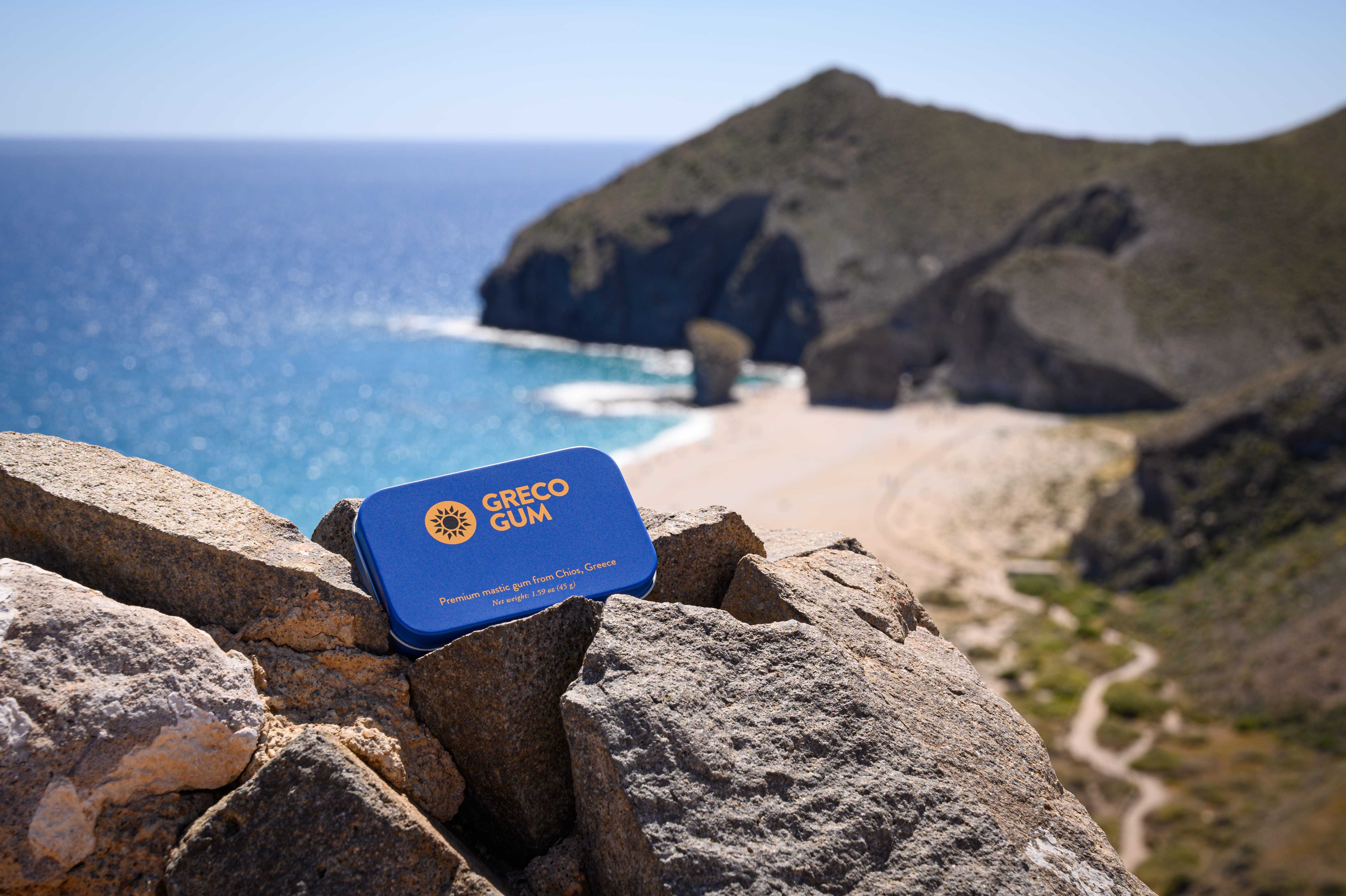 Tin of Greco Gum perched on a cliff side overlooking the Mediterranean Sea.